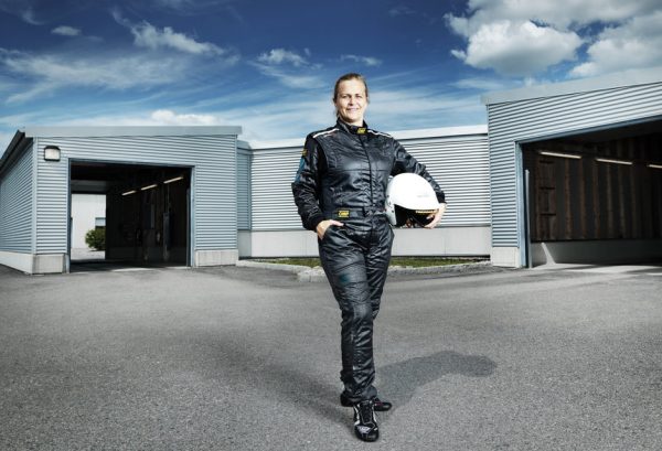 Tina Thörner posing with her helmet in front of a garage